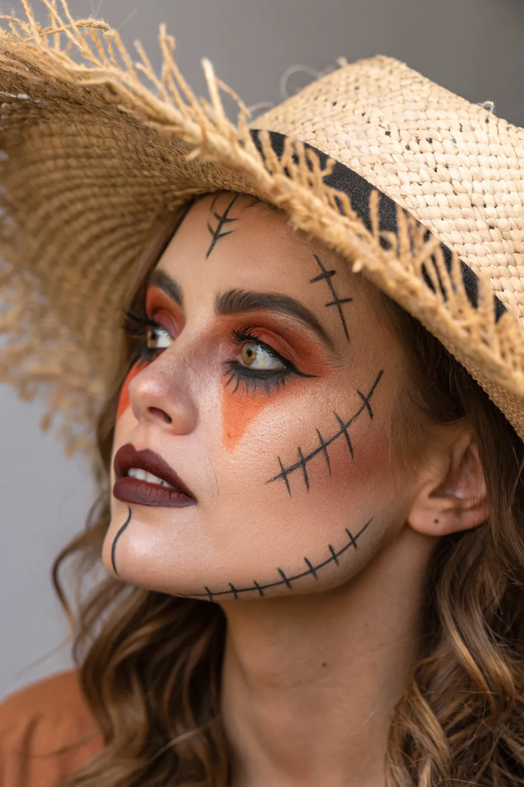 Avant-garde scarecrow face paint with bold stitched seams and asymmetry, runway-ready yet autumnal.
