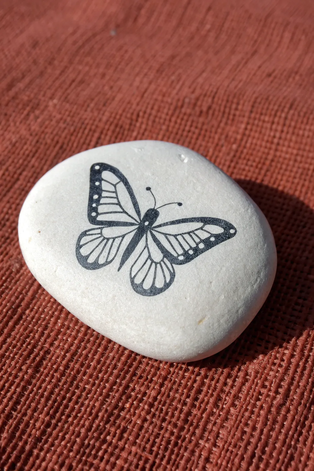 Cut-paper shadow illusion on a white rock with crisp black lines and a soft painted shadow.