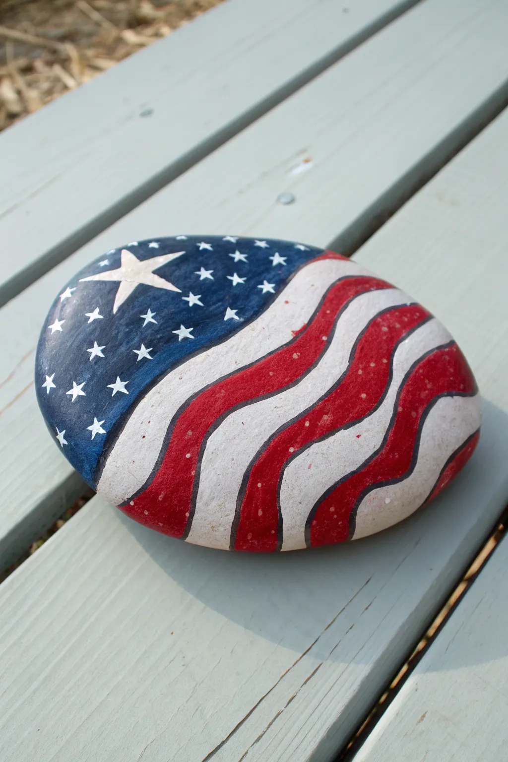 Waving flag ribbon rock painting on a smooth stone, simple and summery 4th of July decor.
