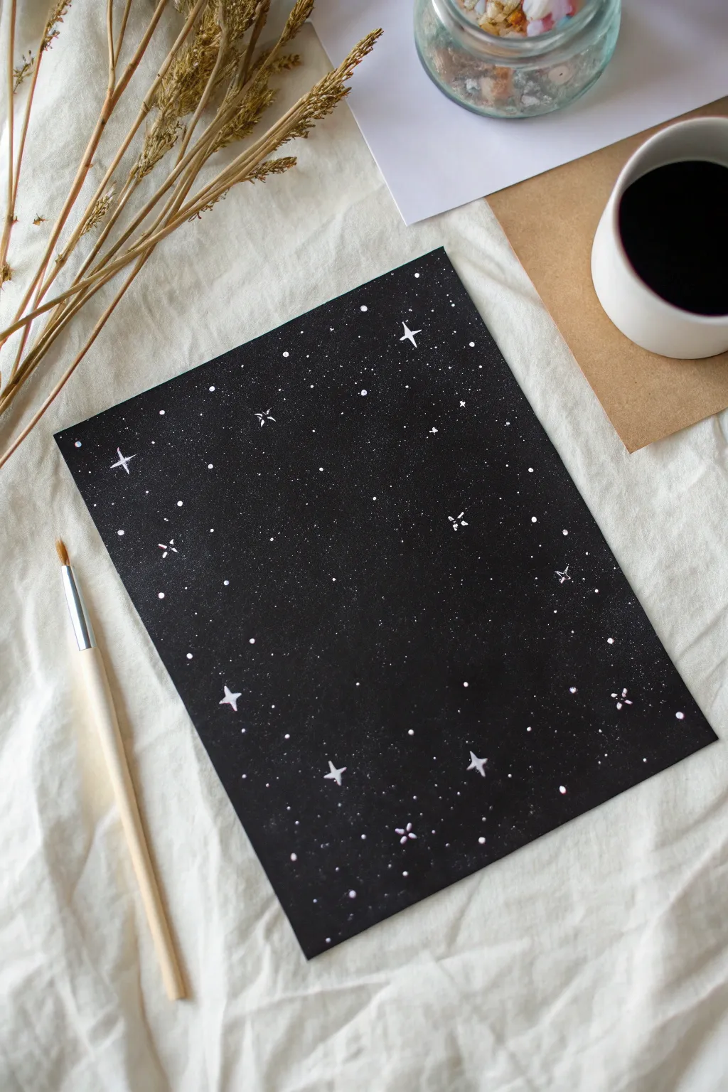 Minimal starry night on black paper with splatter stars and a soft galaxy haze, high contrast.