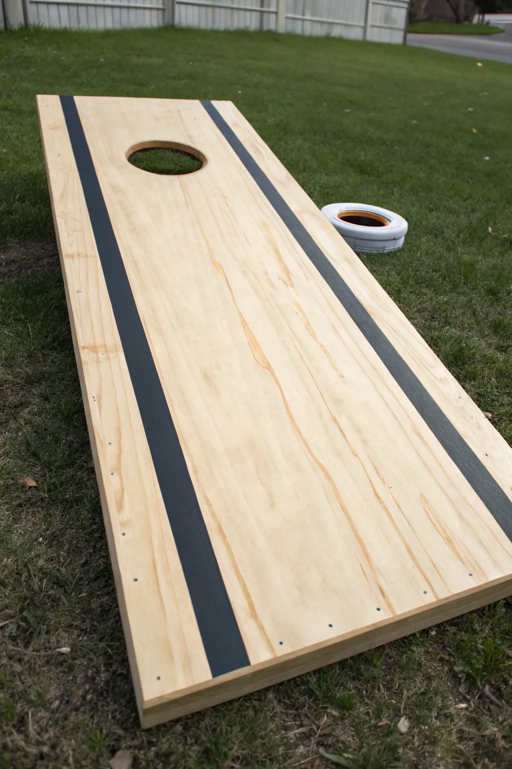 Bold center stripe with crisp taped edges, guiding the eye straight into the cornhole opening.