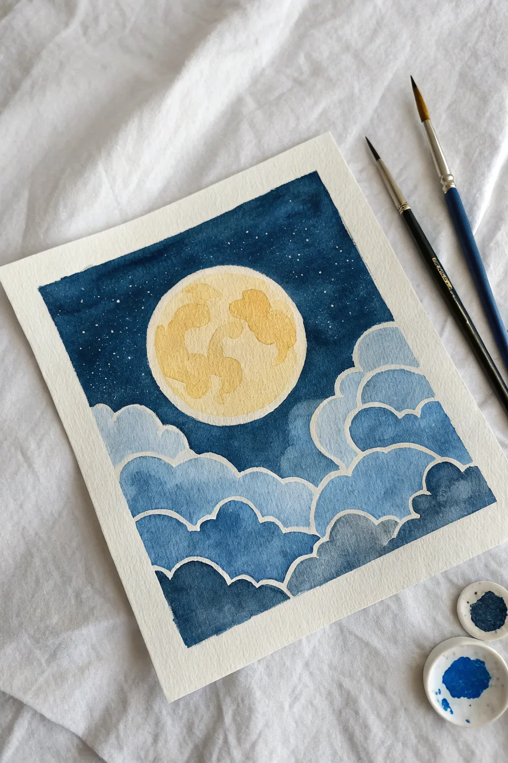 Paint a glowing full moon over dreamy blue clouds with simple layers and calming contrast.