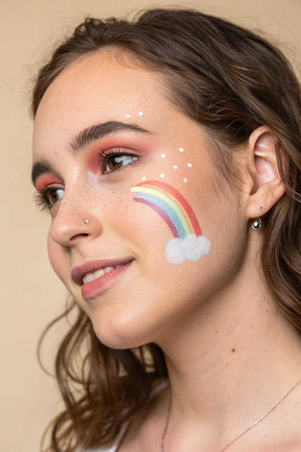 Simple cheek rainbow with puffy cloud and sparkle dots, a cute minimalist face paint idea
