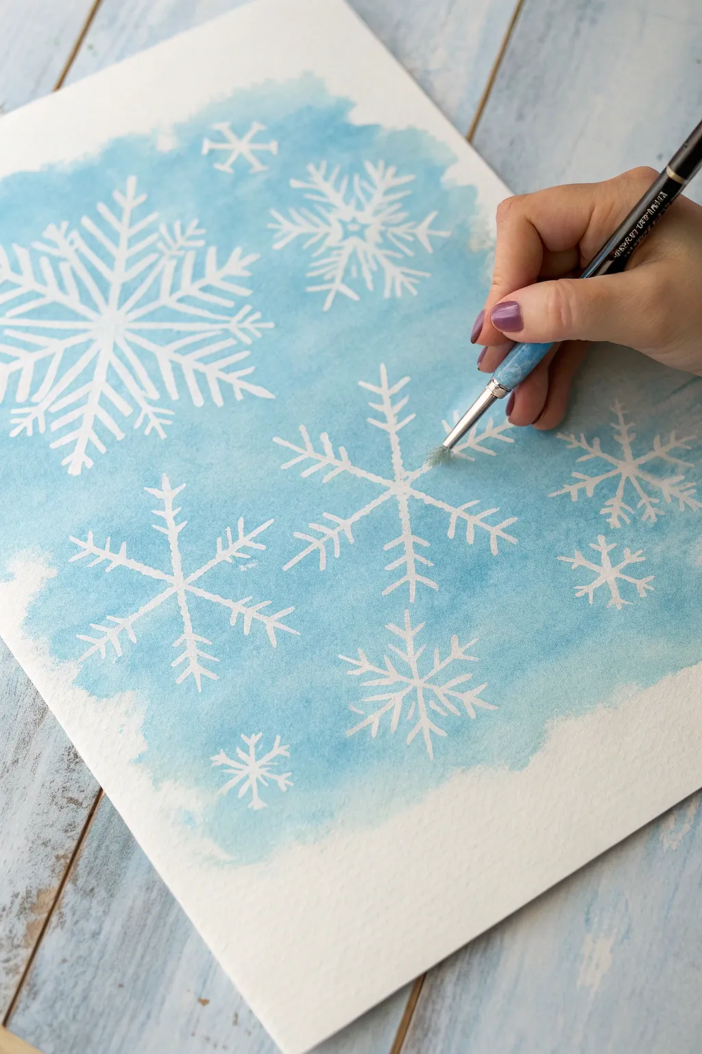 Watch white crayon snowflakes appear as a soft watercolor wash blooms across the paper.