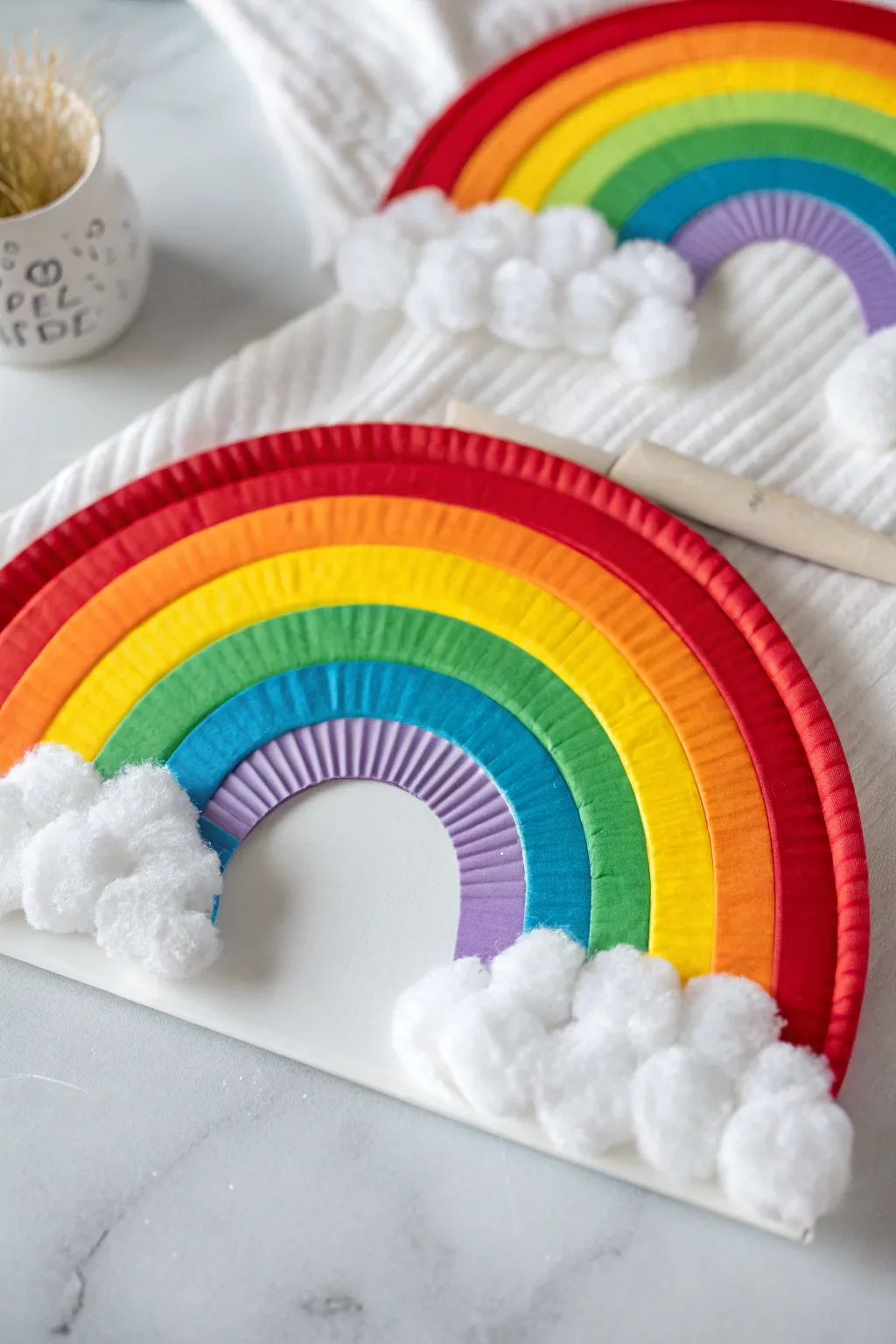 Bright paper plate rainbow with fluffy cotton clouds, a simple Scandinavian-inspired kids craft.
