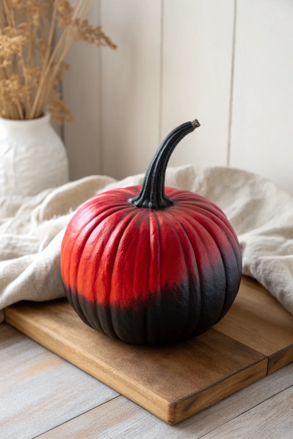 A sleek red-to-black ombre pumpkin centerpiece with minimalist Scandinavian warmth and contrast