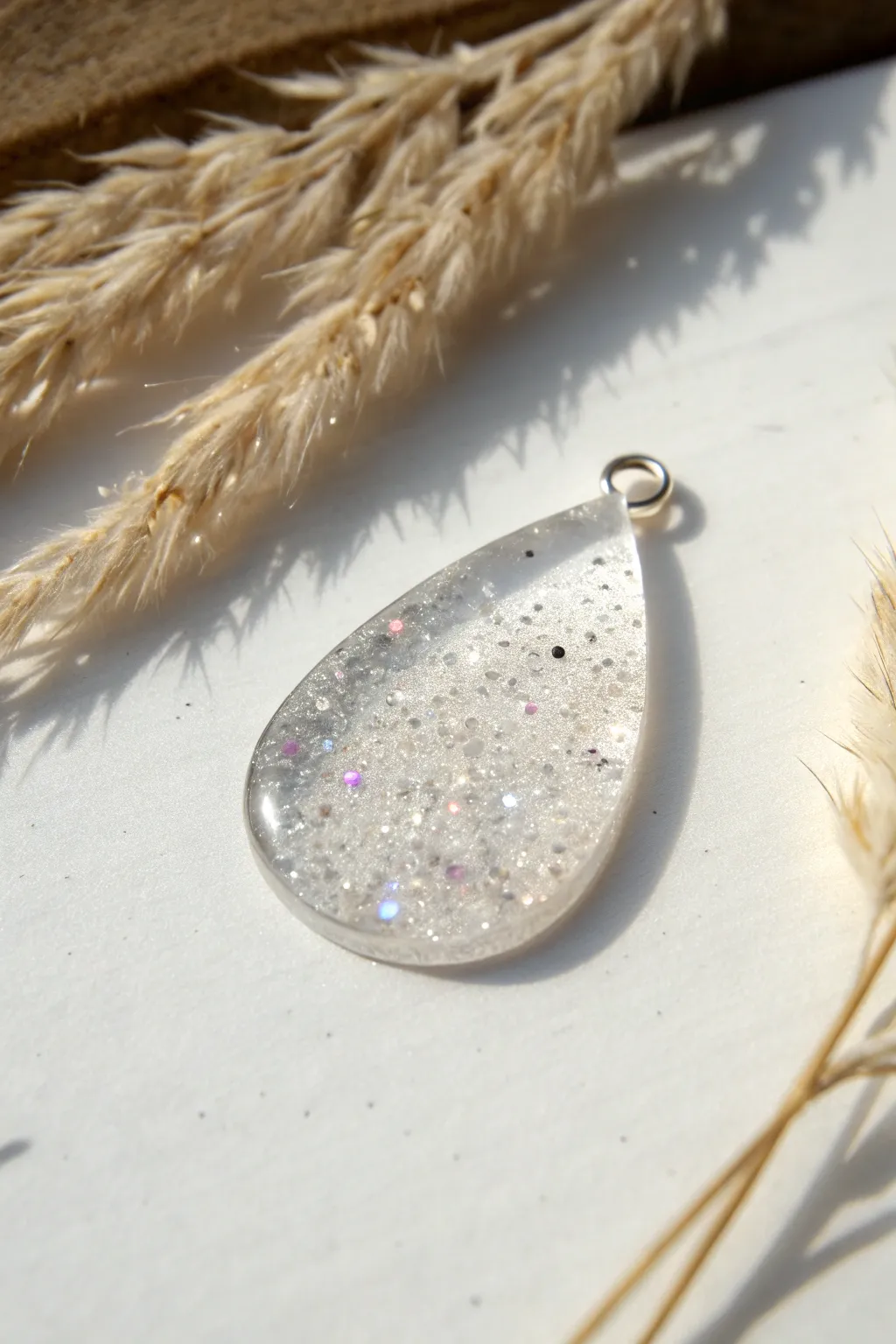 Glitter gradient resin teardrop charm on white, soft sparkle fading from bold to bare.