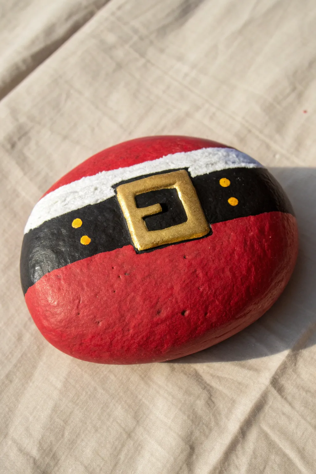Paint a bold Santa belly belt buckle on a smooth round rock for an easy festive centerpiece.
