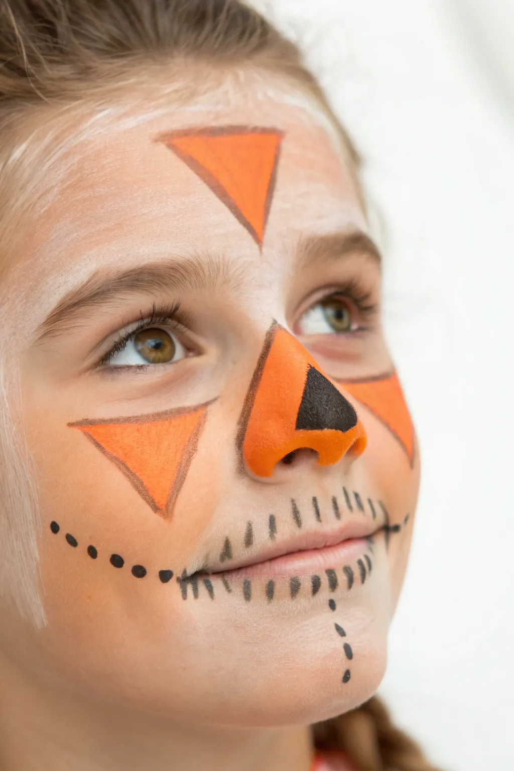 Bright orange triangle nose with black stitch outline and blush cheeks for chic scarecrow charm