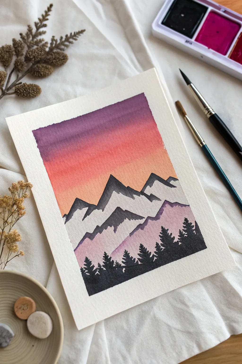 Mountain range at dusk: bold black silhouette over a smooth sunset gradient fading into purple