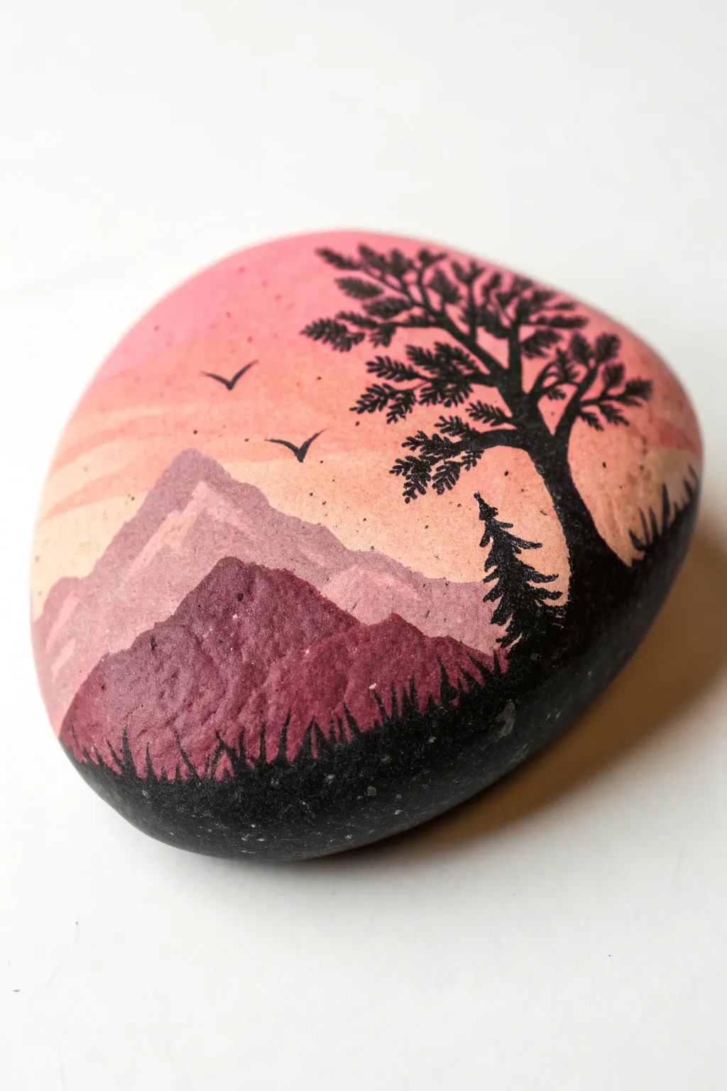 Paint a pink sunset gradient rock with a crisp black silhouette for calm boho vibes.