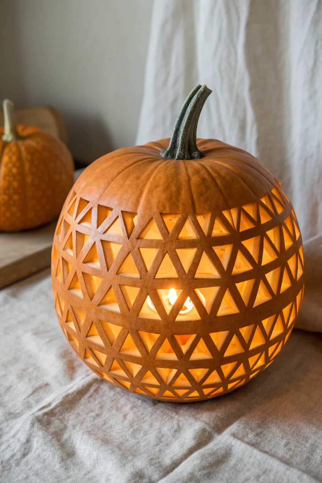 Modern geometric grid pumpkin lantern, softly glowing in a calm Scandinavian minimal setting