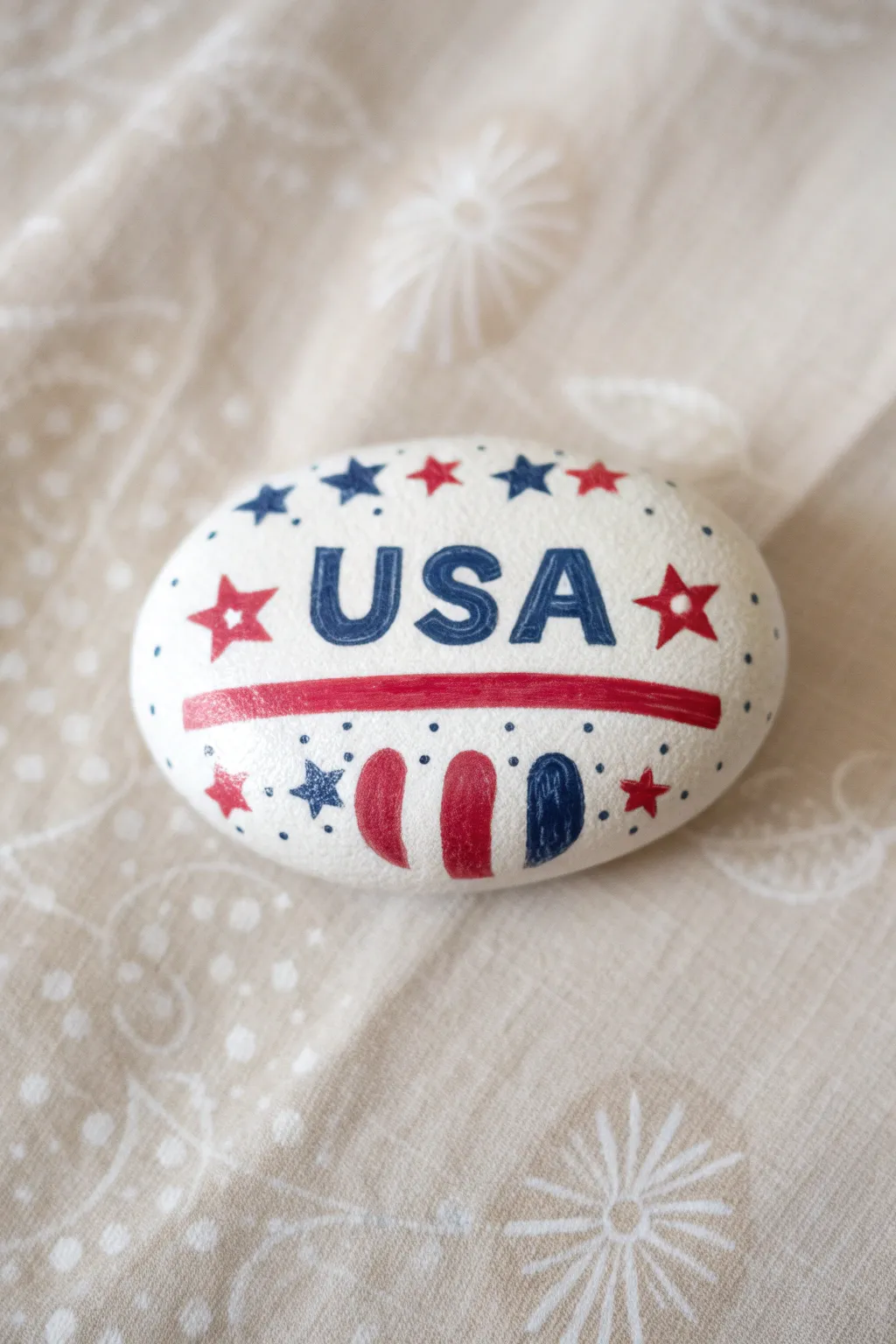Minimalist July 4th rock craft: bold USA block lettering with stars and stripes, ready to paint.