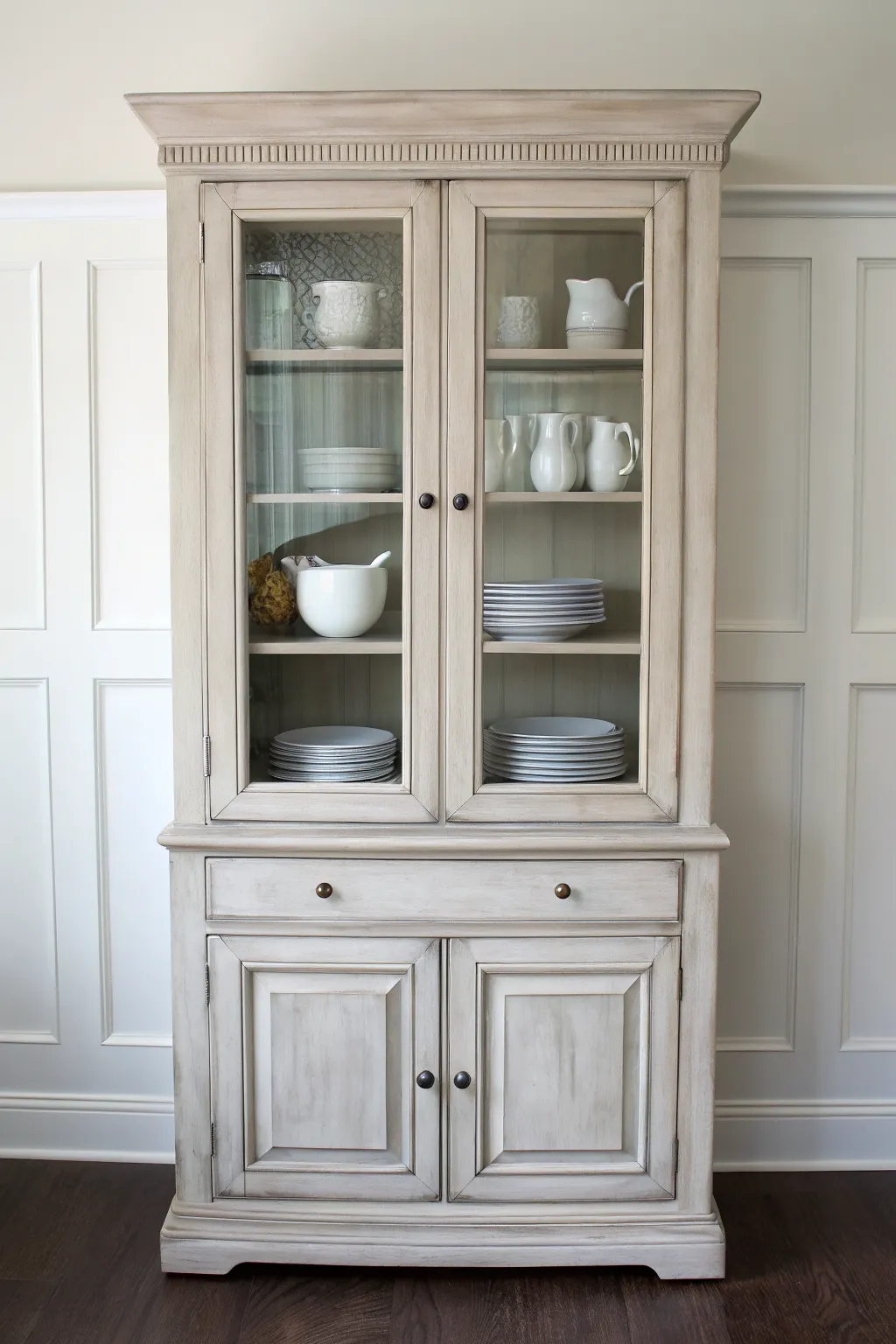 Light greige chalk-painted china cabinet blending into wall, styled with simple white china.