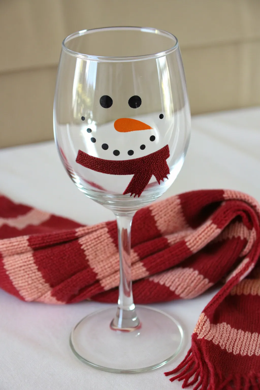 Minimal snowman wine glass with cozy scarf band and delicate snow dots, clean Nordic style