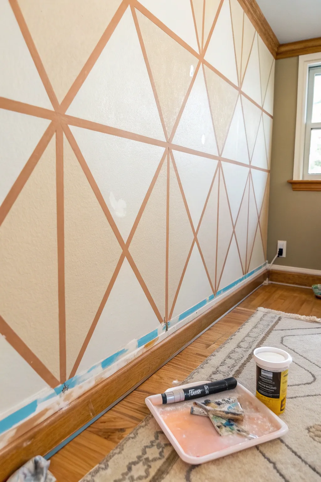 Crisp painters tape triangles mid peel, revealing sharp edges for a modern geometric wall.