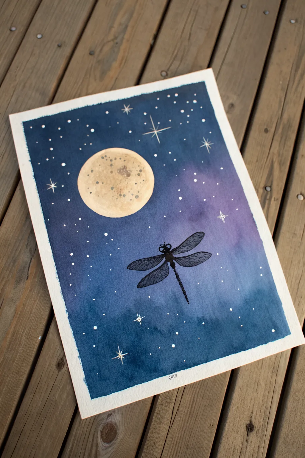 Moonlit dragonfly silhouette painting with a glowing moon, deep indigo sky, and starry speckles.