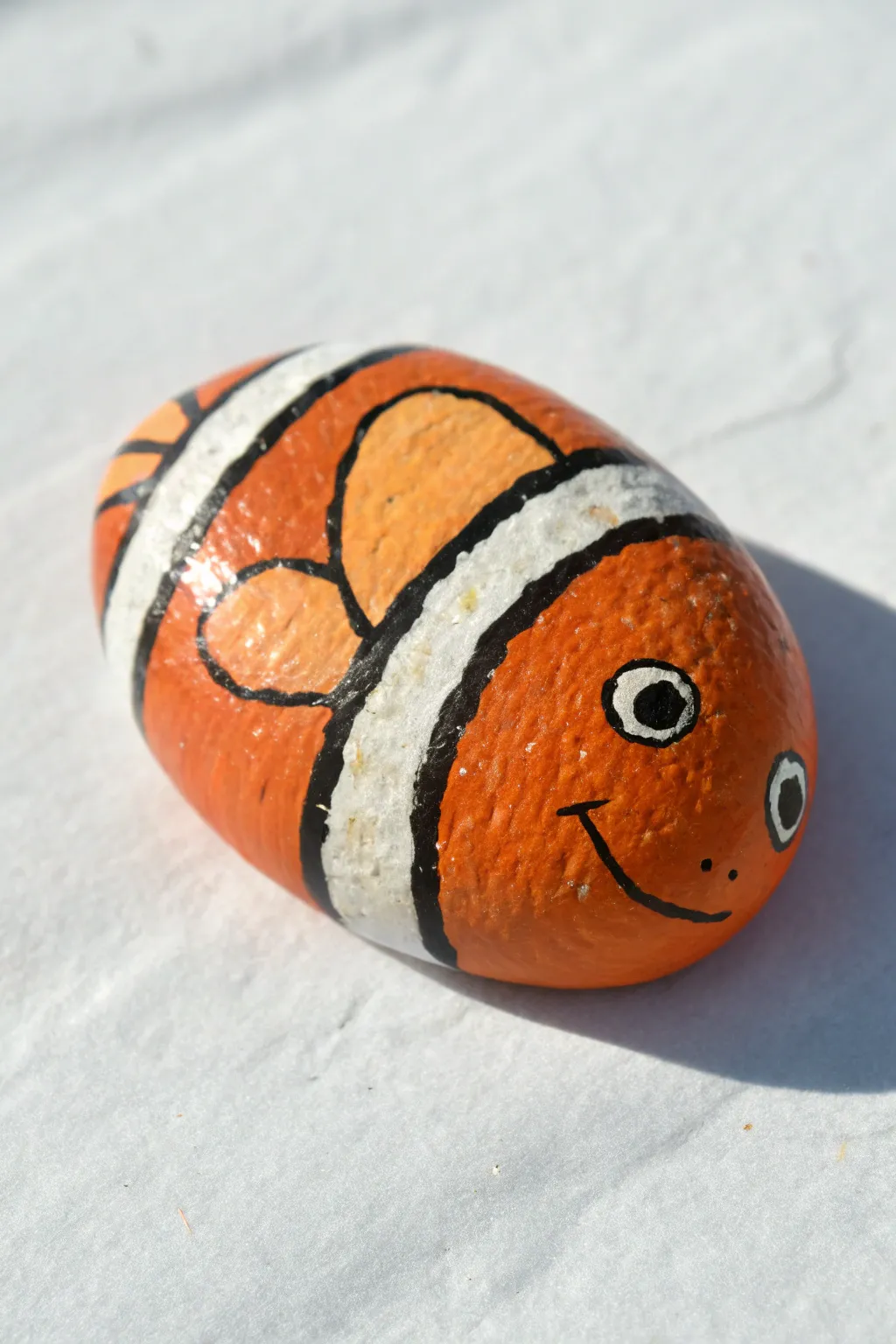Bold banded clownfish rock painting with bright orange stripes on crisp white for maximum pop