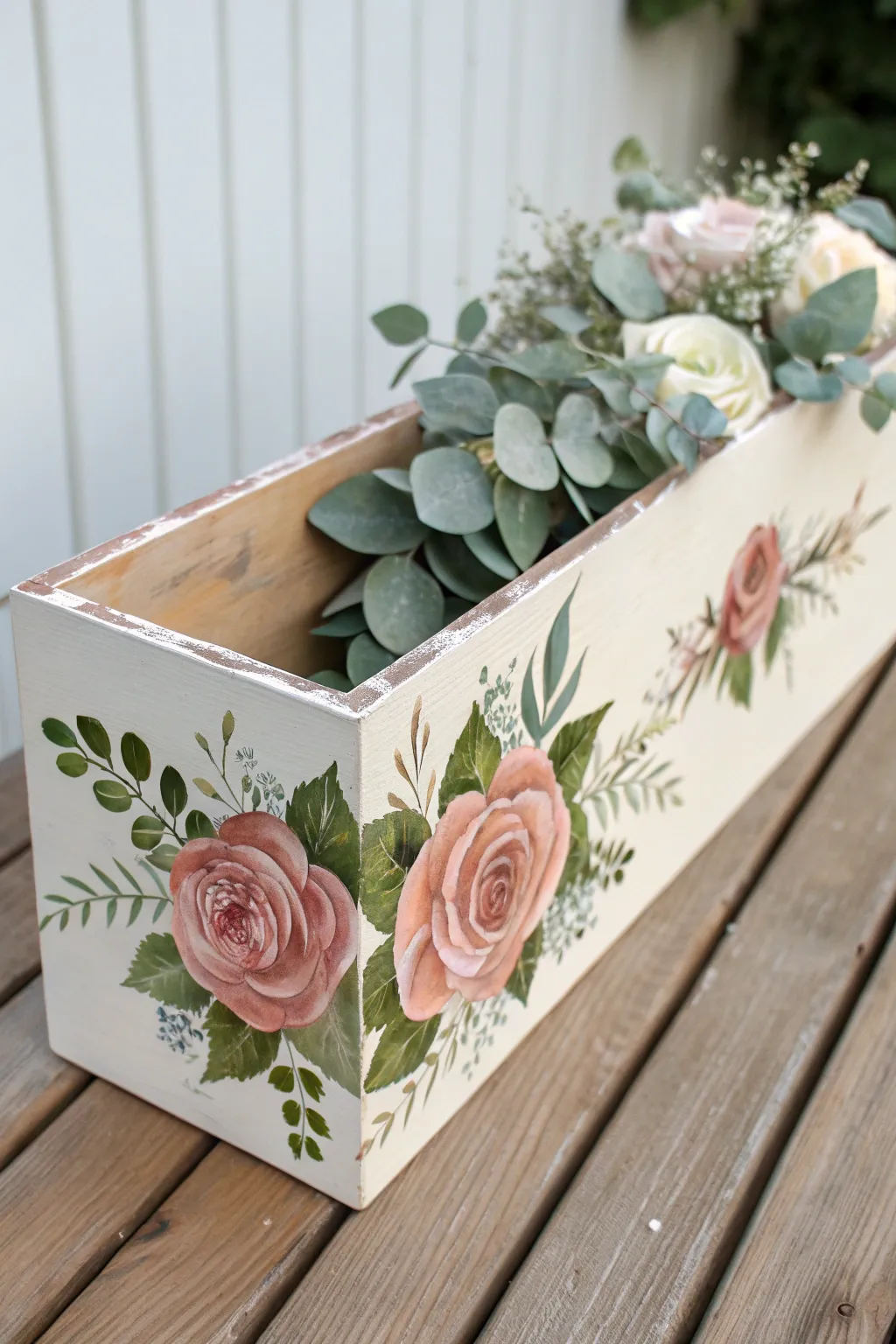 Rose garland along the rim of a simple flower box, minimalist cottage charm with soft contrast.