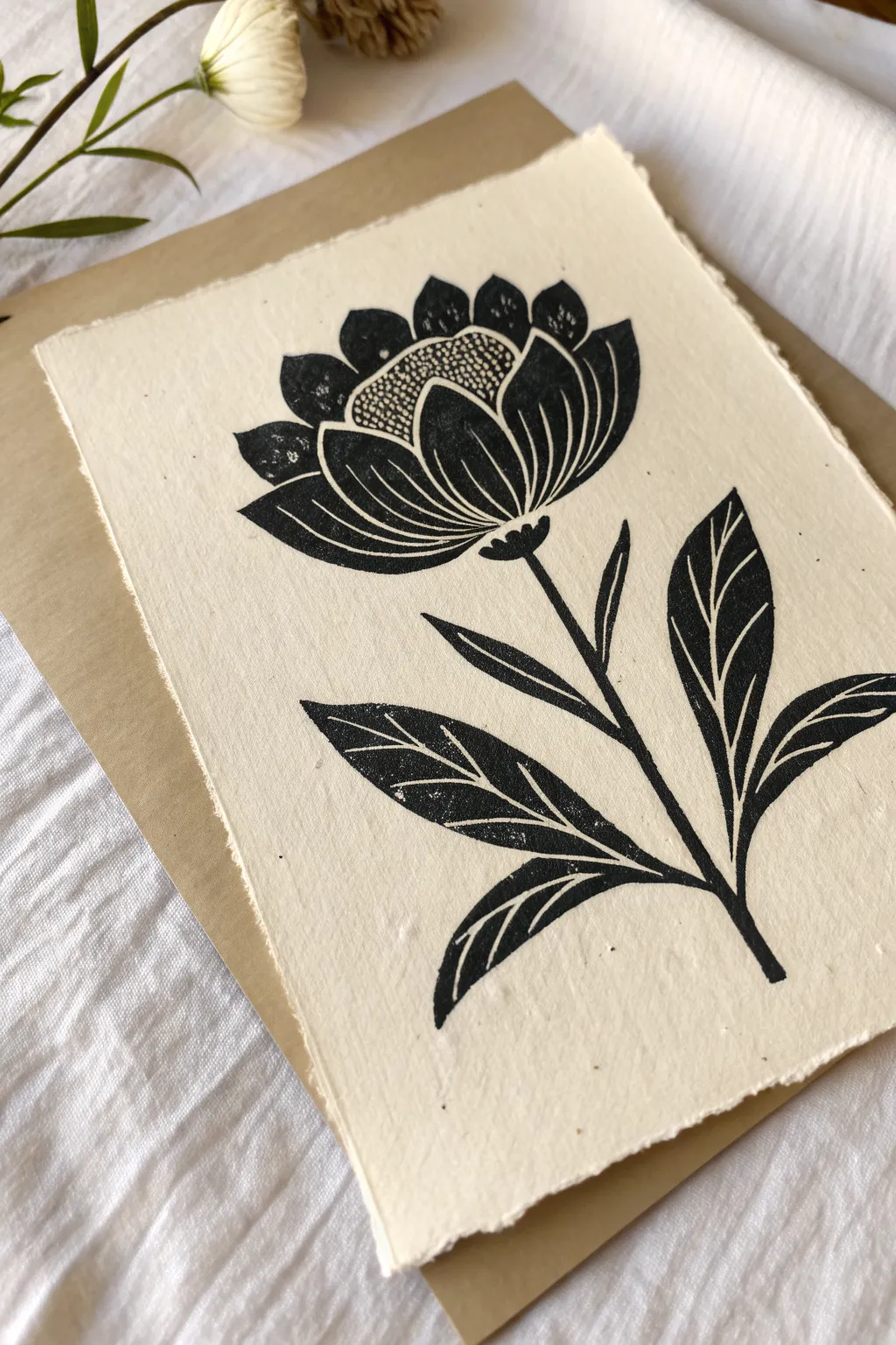 Single bloom linocut idea: bold black shapes with delicate carved highlights on warm paper.