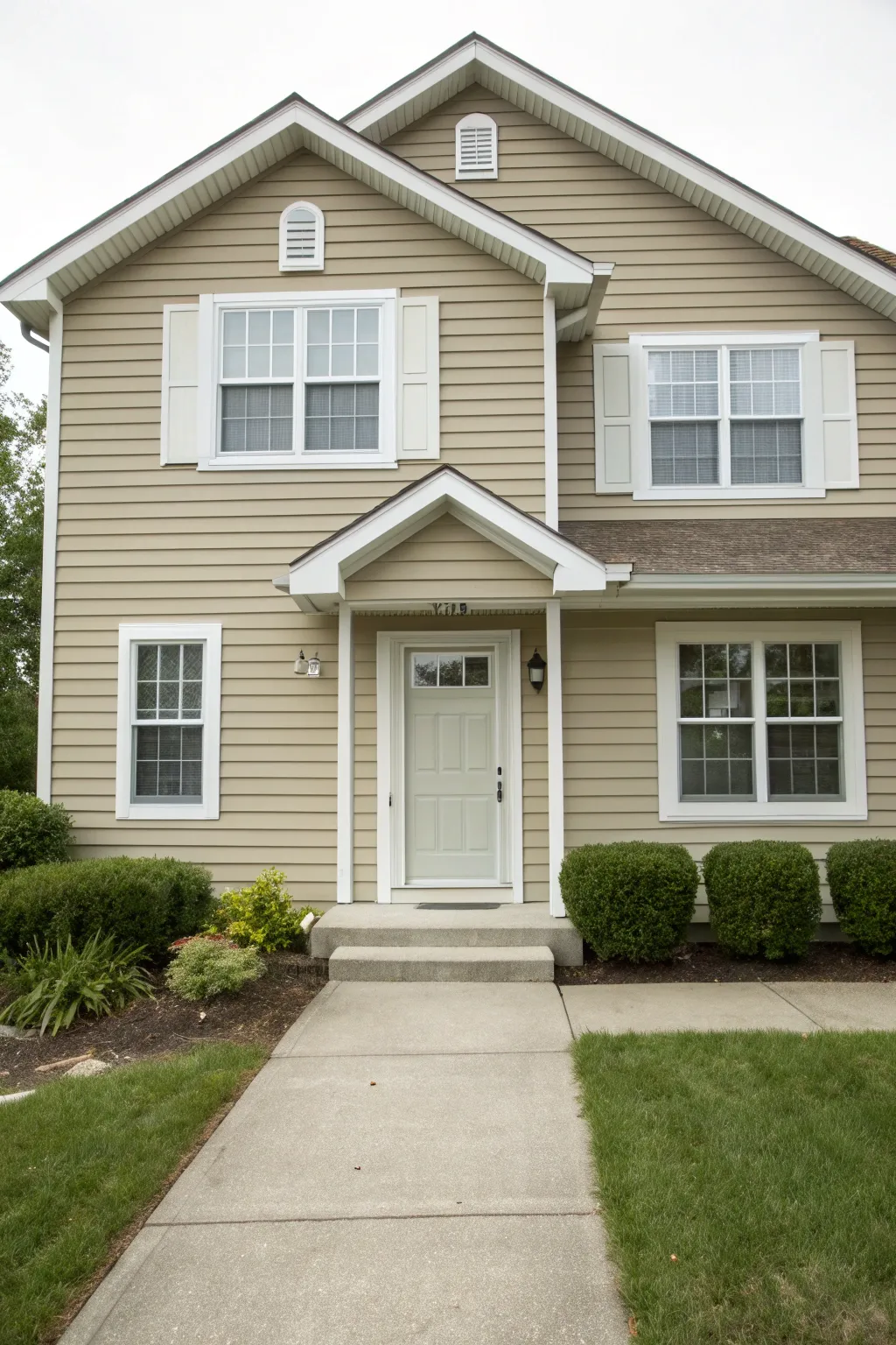 Greige exterior with crisp white trim and simple shrubs for calm, modern curb appeal.