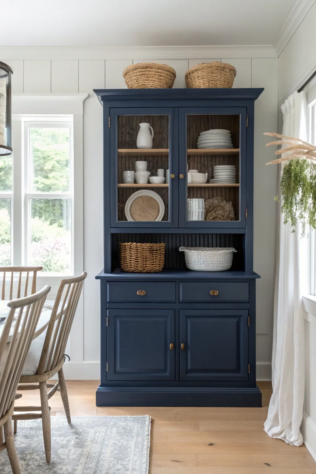 Deep navy painted hutch in a bright dining room, styled in soft whites for bold contrast