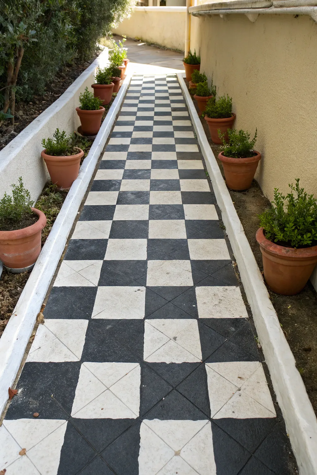 Crisp black-and-white checkerboard entry walkway with clean edges and simple potted greenery.