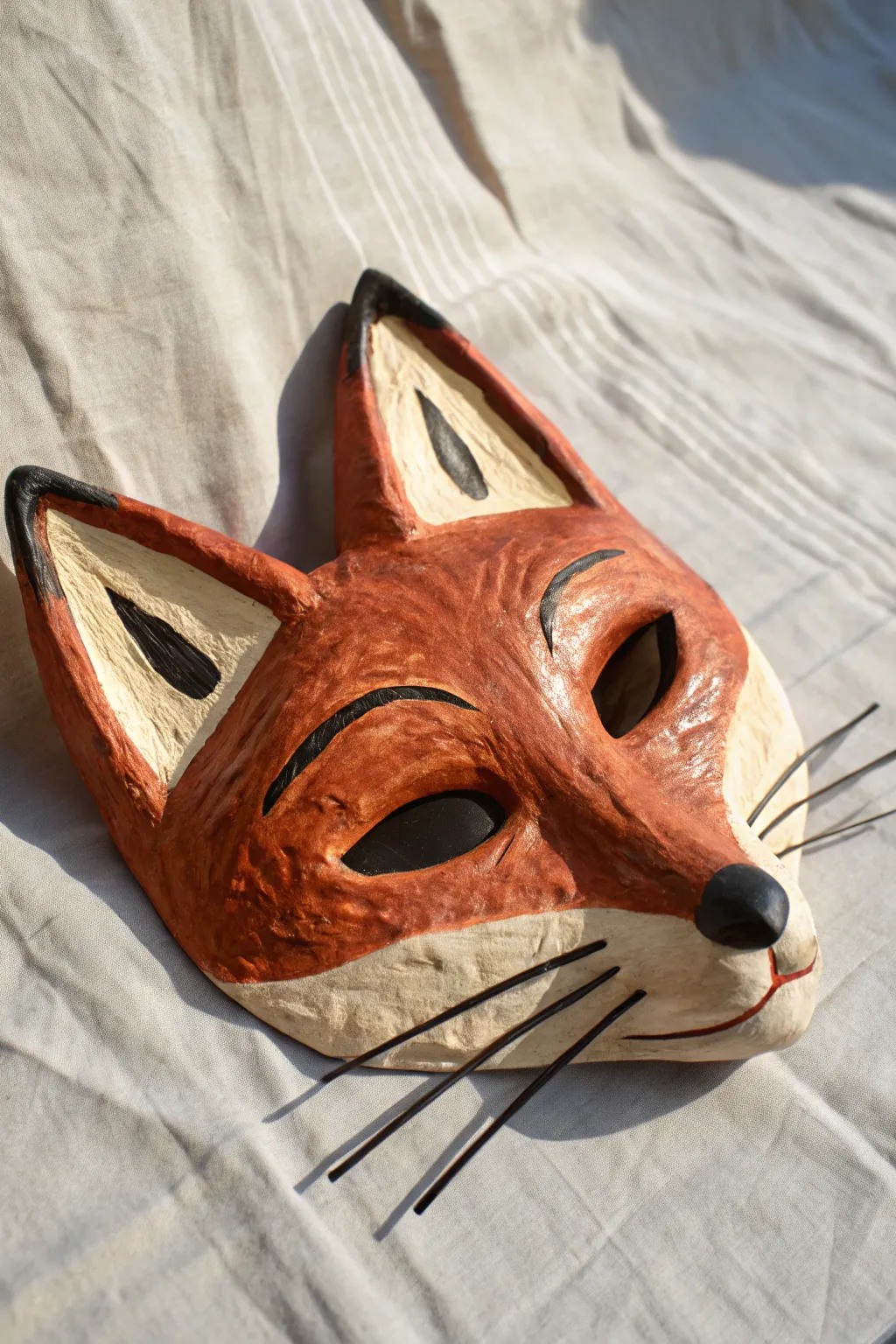 DIY plaster fox mask with simple paper ears, warm tones, and crisp whisker lines