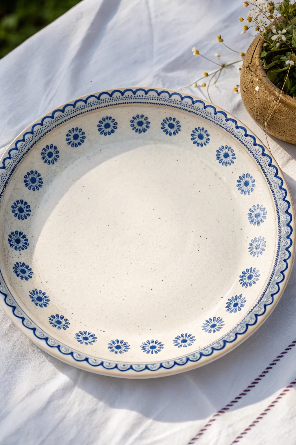 Blue-and-white border motifs on a simple platter rim with petals, dots, and scallops in cobalt