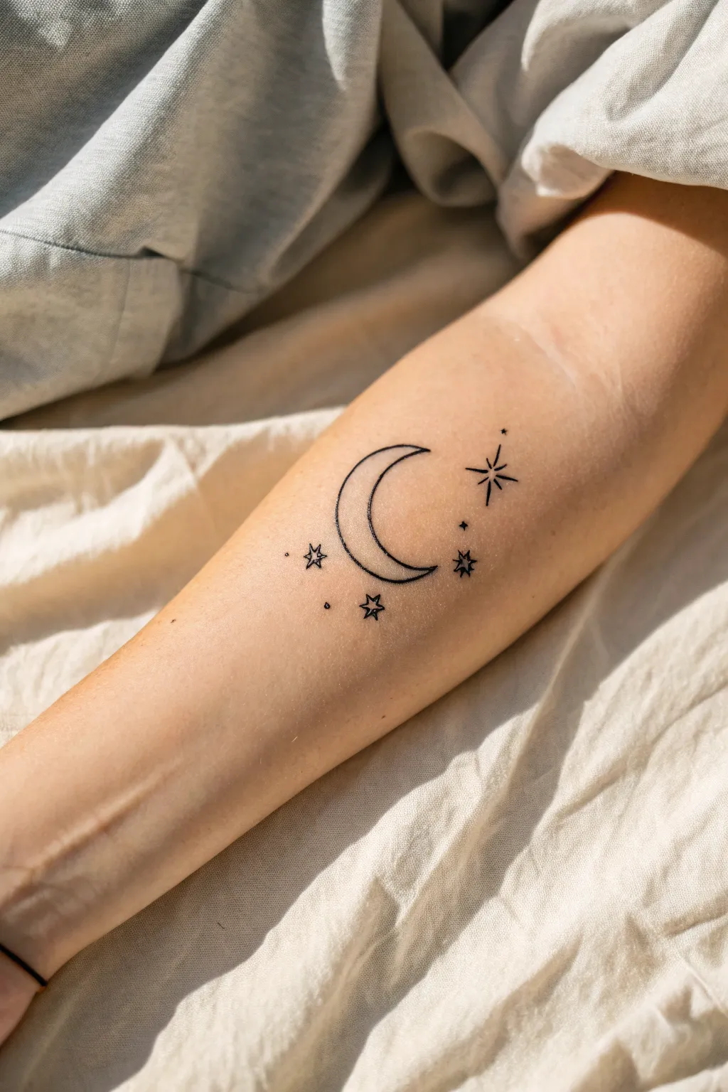 Minimal crescent moon with tiny stars in blackwork, clean contrast and delicate craftsmanship