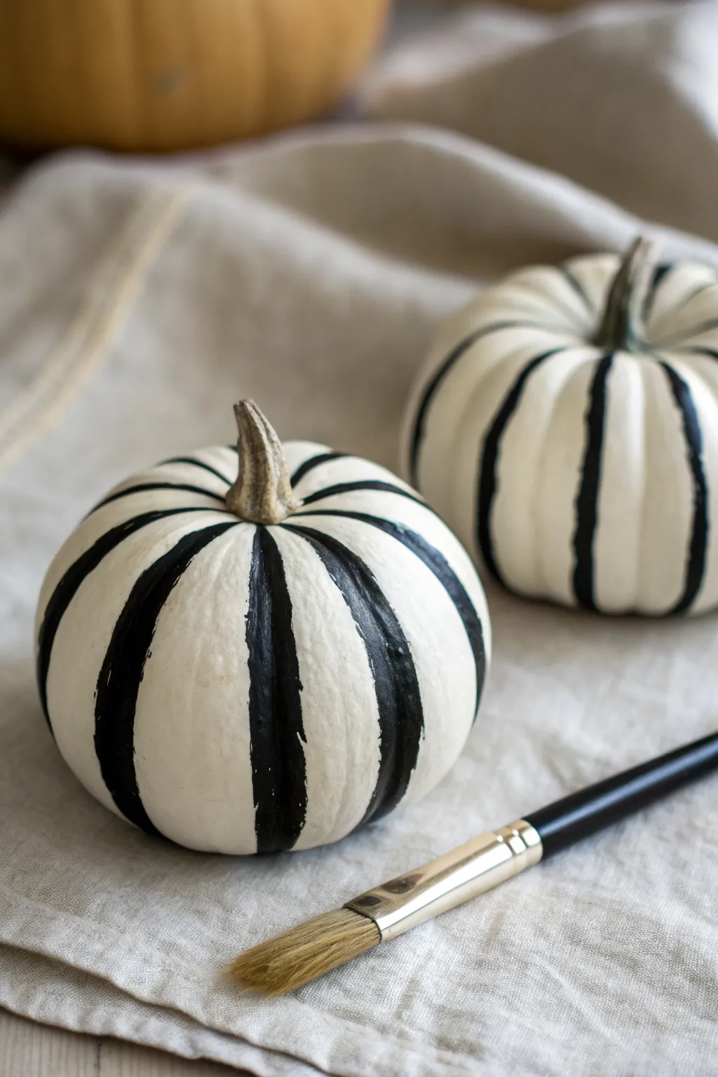 Minimal black-and-white striped mini pumpkin with a fine brush for chic fall DIY inspiration