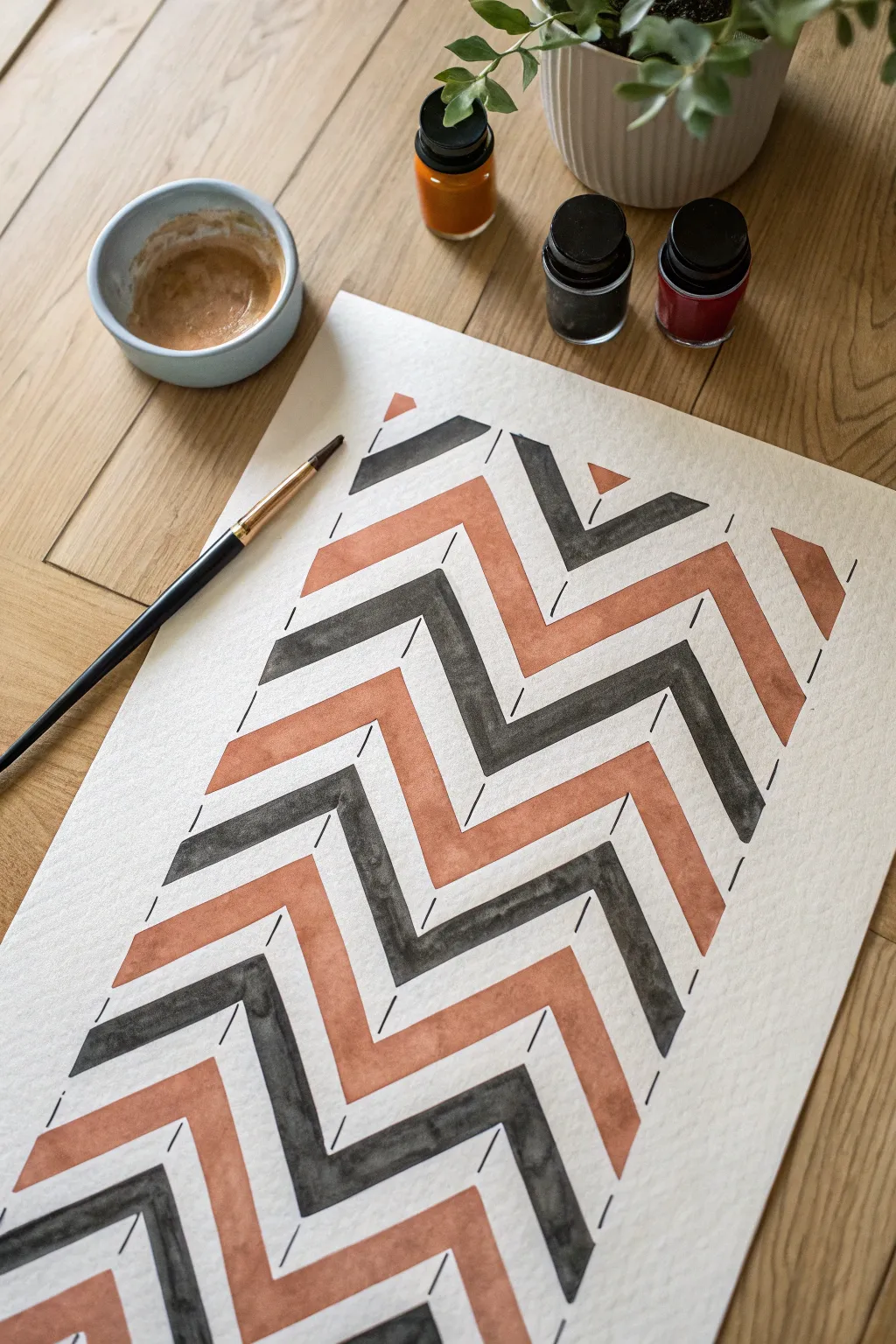 Crisp chevron tape art in terracotta and charcoal on clean paper, minimalist studio mood.