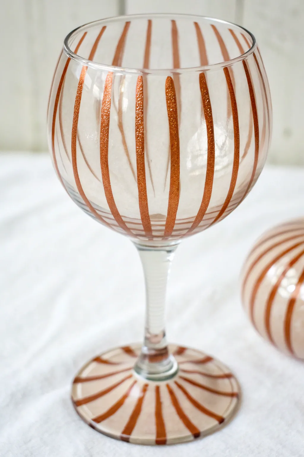 Minimalist wine glass with bold vertical stripes that hug the bowl and echo on the stem