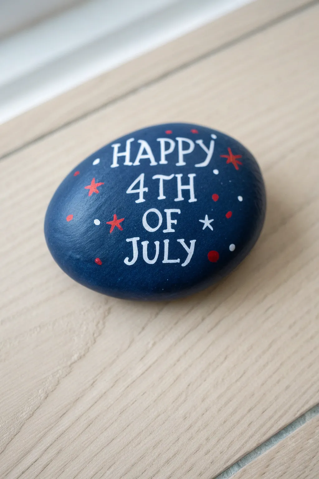 Elegant navy 4th of July script rock with bright white lettering and tiny red star accents