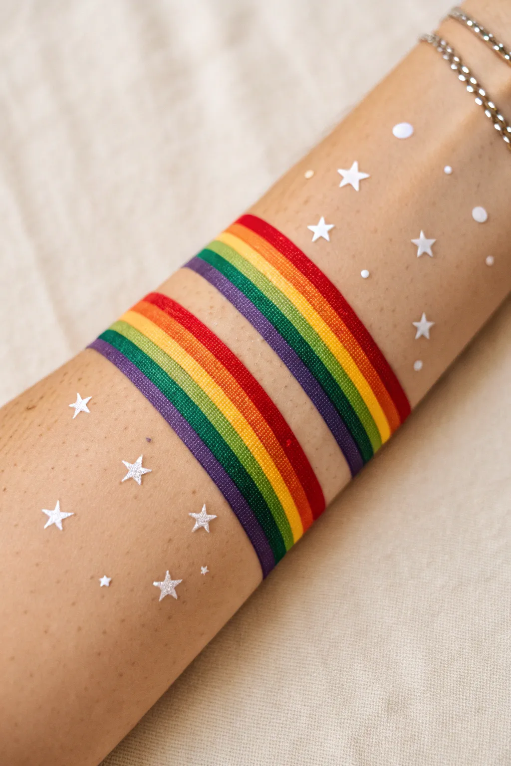 Easy rainbow swipe arm paint with delicate white star sprinkles, bold color on clean skin