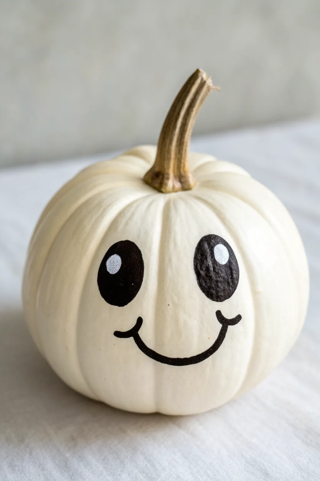 Simple high-contrast smiley baby pumpkin with sweet oversized eyes in minimal boho style