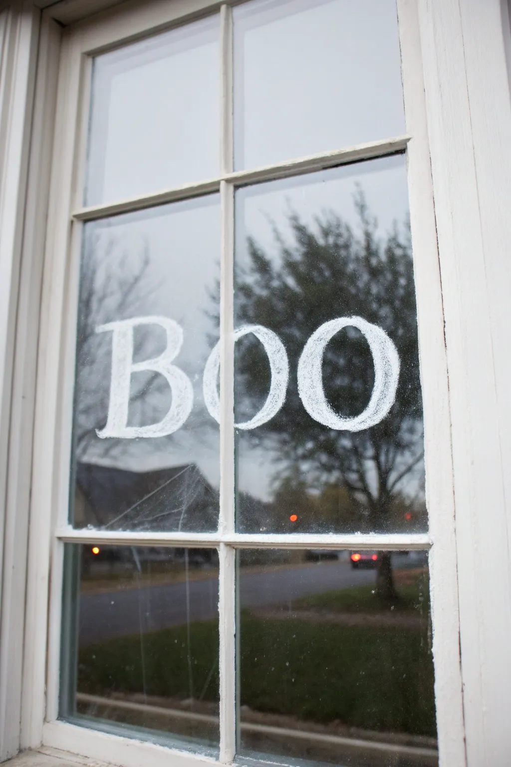Minimalist Halloween window paint with bold BOO lettering, delicate web corners, and subtle depth