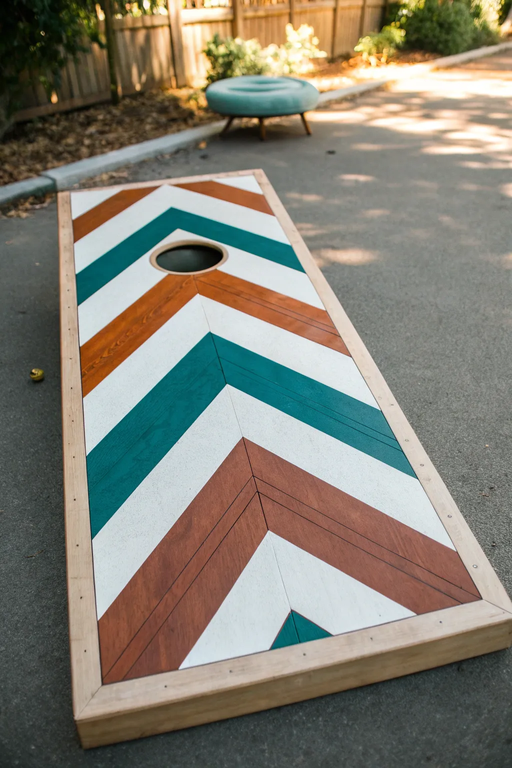 Bold chevron tape-resist lines in teal and terracotta for a clean, sporty cornhole board.
