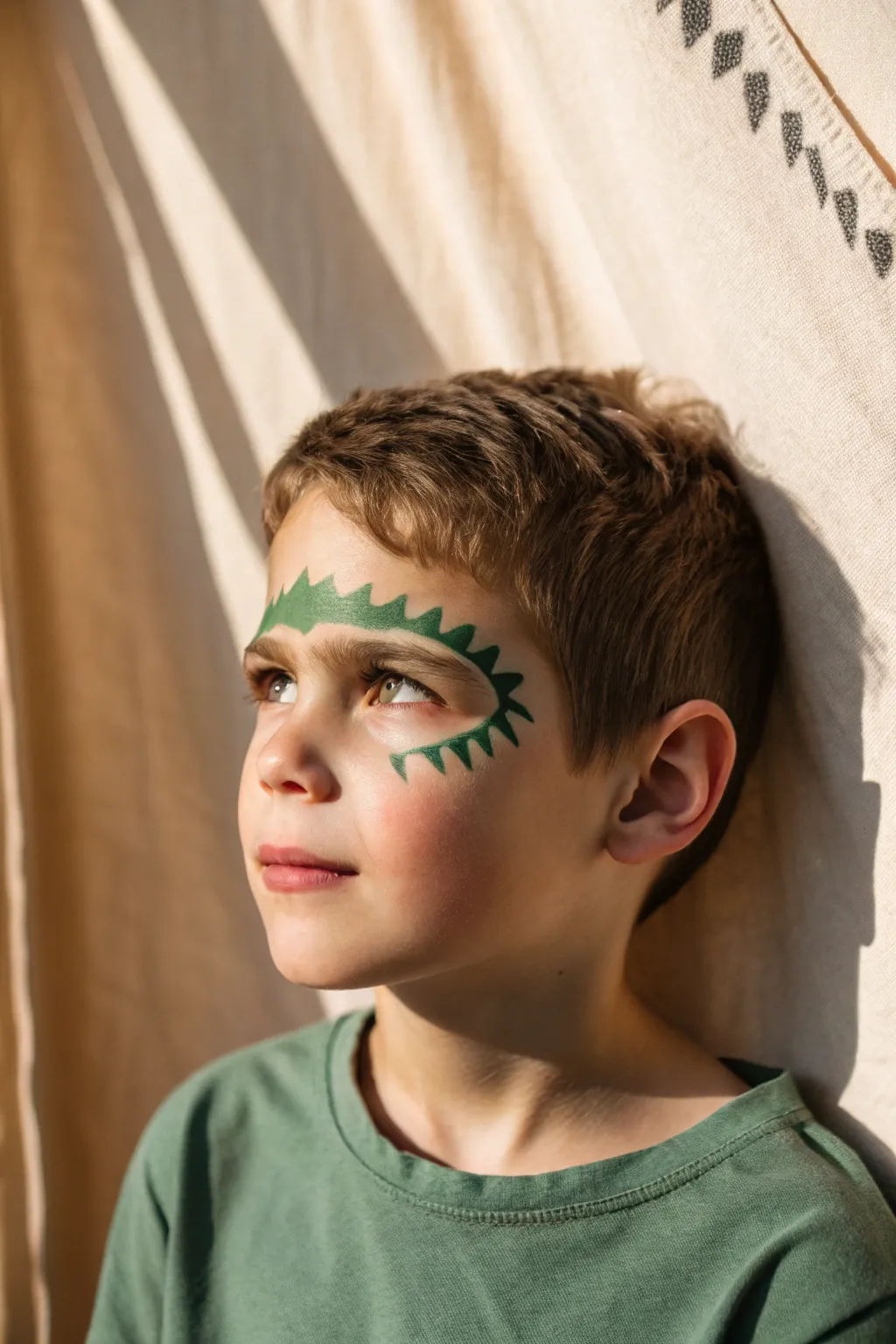 Easy dinosaur scales face paint around one eye, bold green and dark spikes for a playful boy look