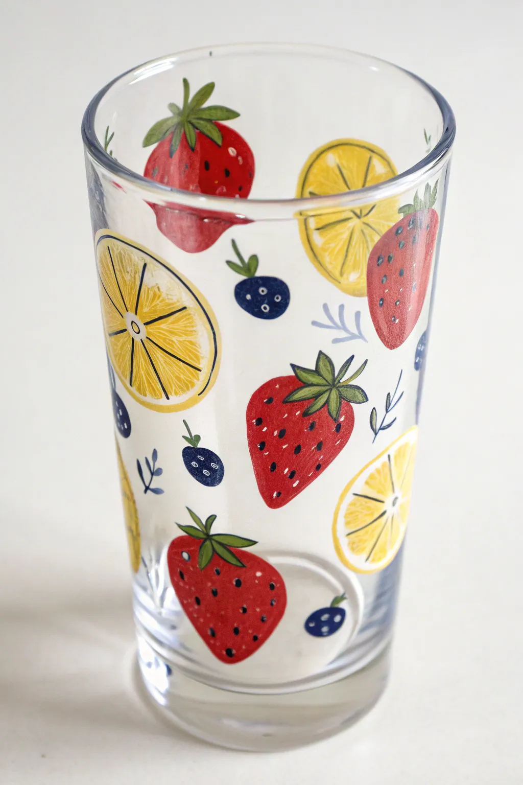 Fresh citrus and berry doodles on a hand-painted glass cup, bright colors magnified by water.