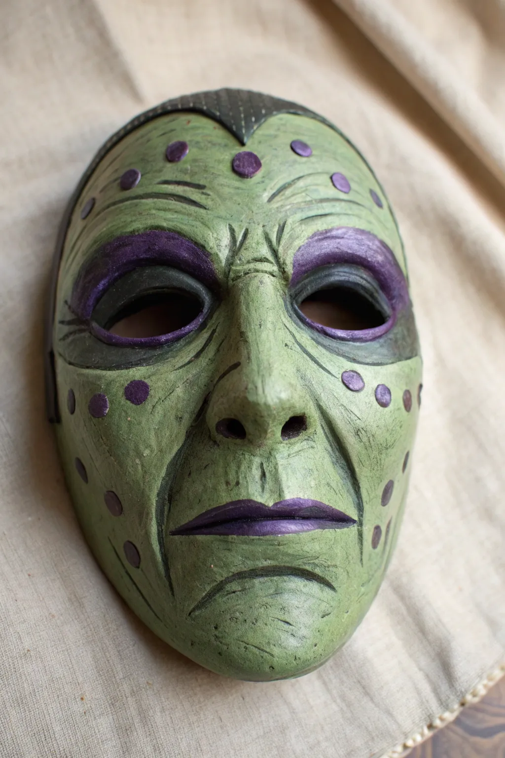 Witchy green mask with sculpted shadows and tiny warts for an elegant spooky DIY.