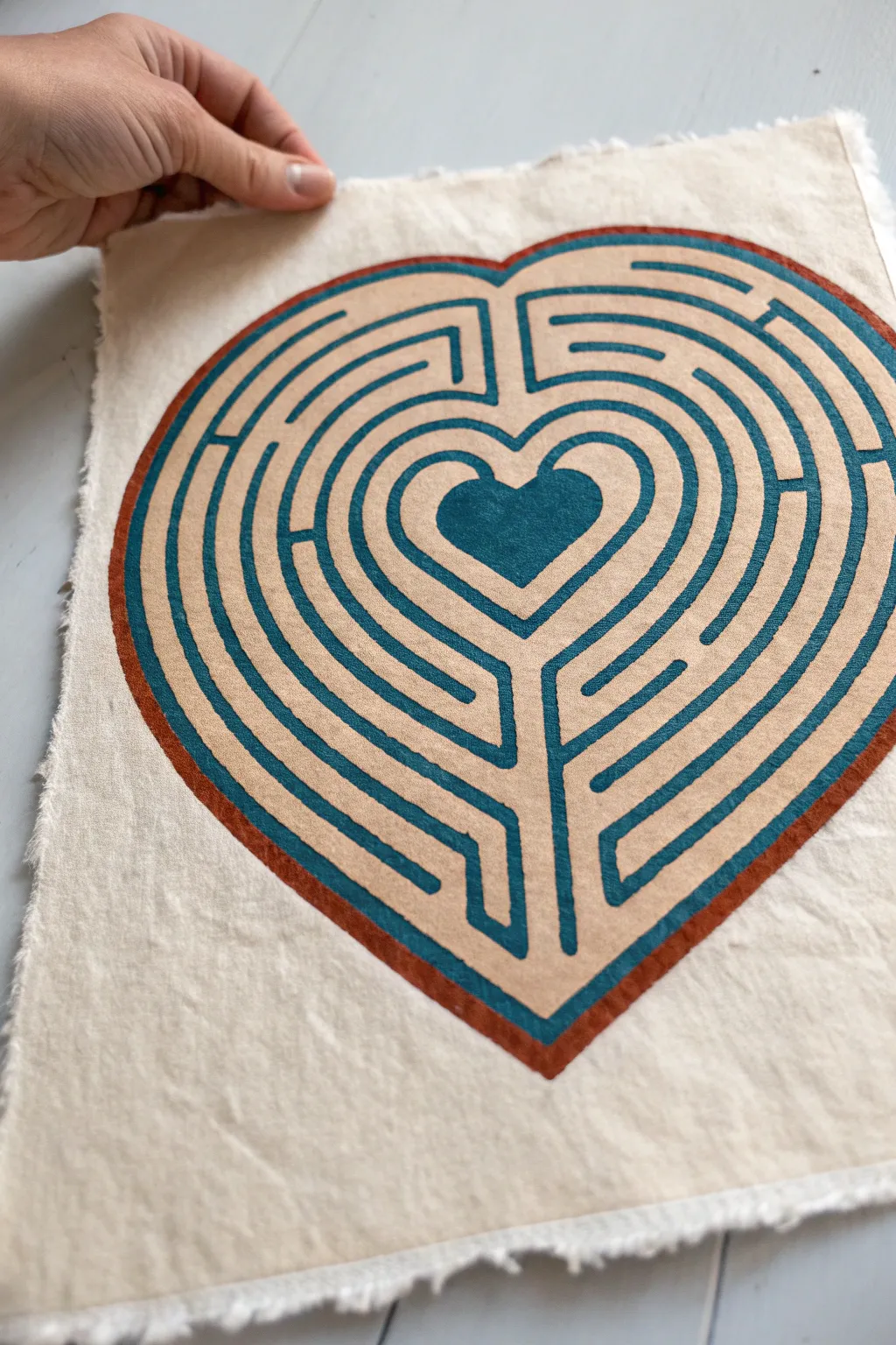 Heart shaped maze outline with bold teal lines on ivory paper, minimal yet playful and crafty.