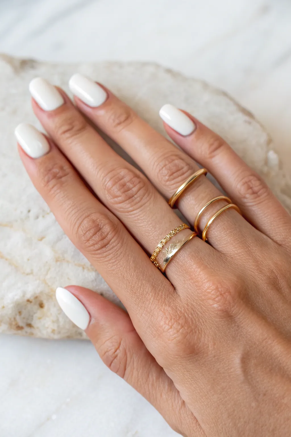 Milky white minimal manicure on short squoval nails, clean and soft with simple gold rings.
