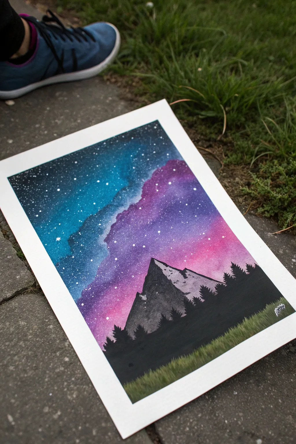 Bold spray paint galaxy above a jagged black mountain silhouette, simple and striking poster art.