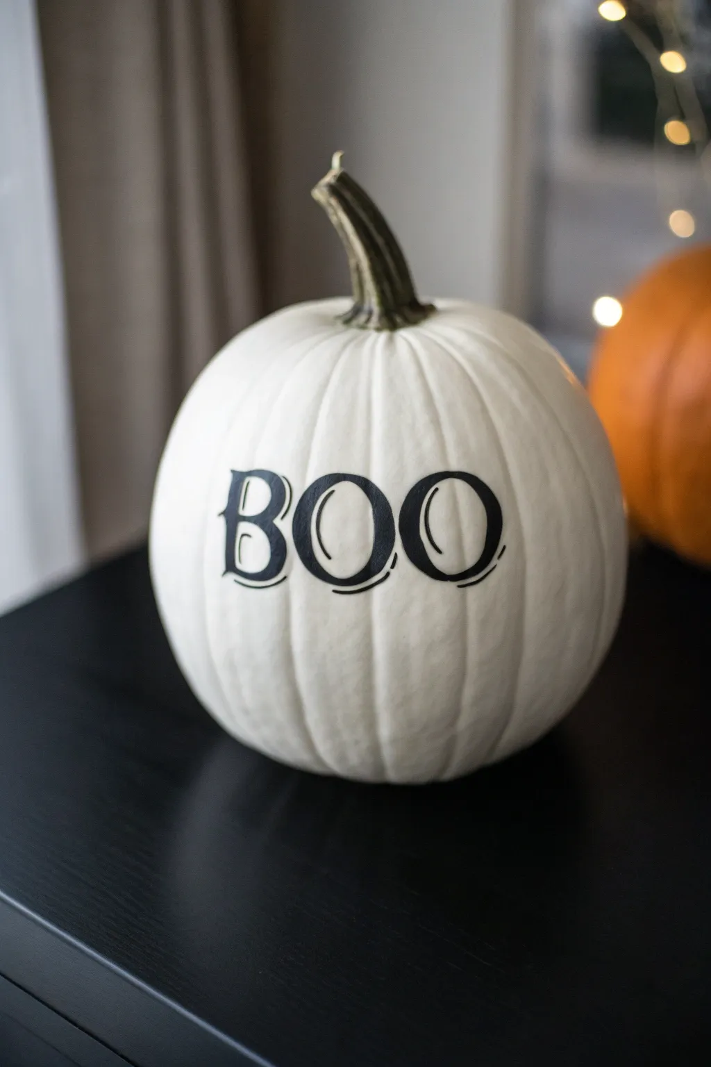 Moody gothic black lettering on a white pumpkin, minimalist Scandinavian boho Halloween decor.