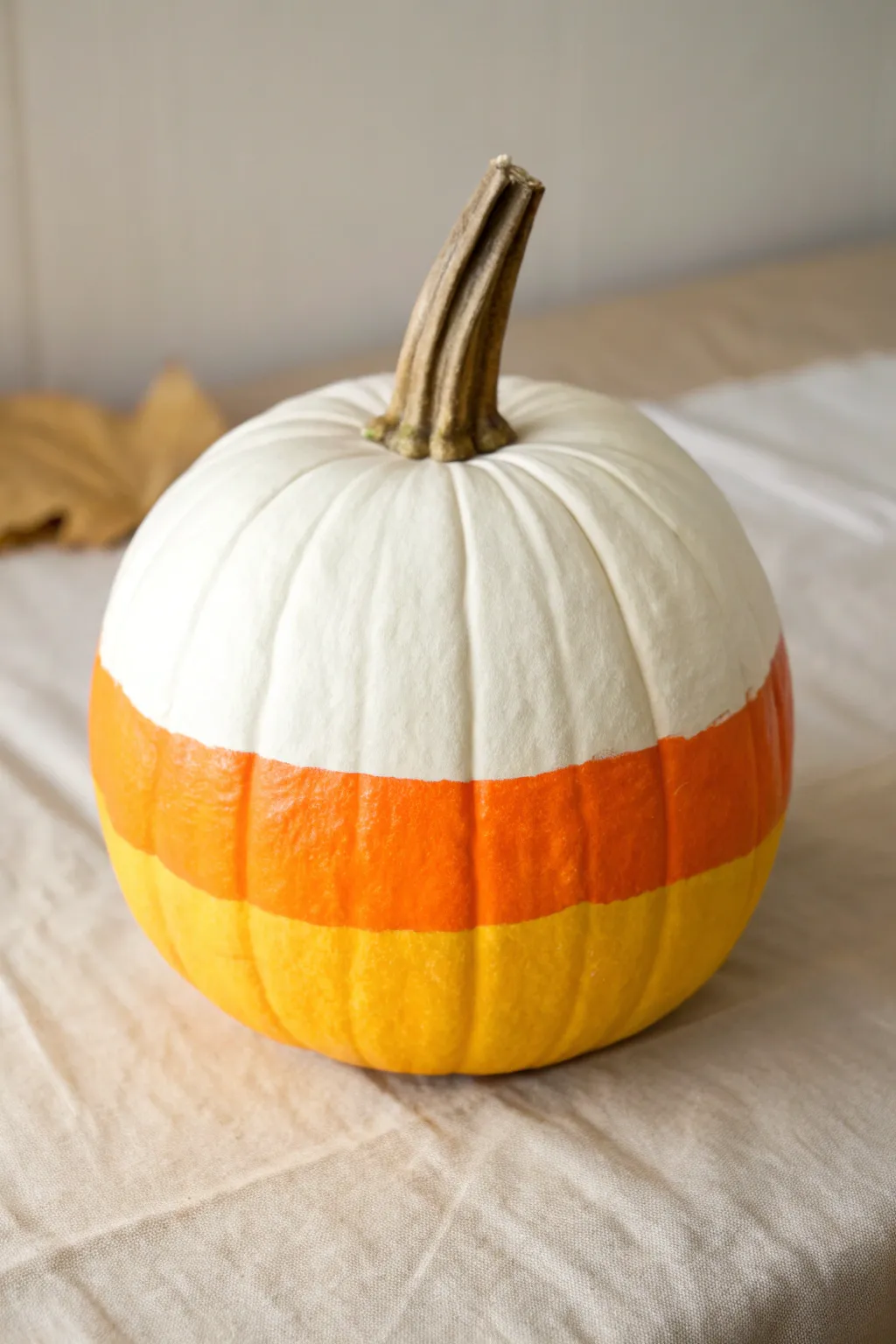 Candy corn color-block pumpkin with clean stripes, a minimalist painted calabaza idea for fall