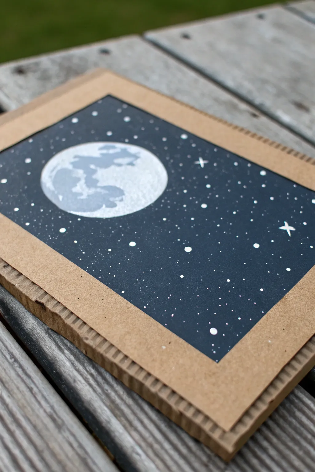 DIY night sky on cardboard: deep indigo, crisp moon, and delicate star splatter texture.