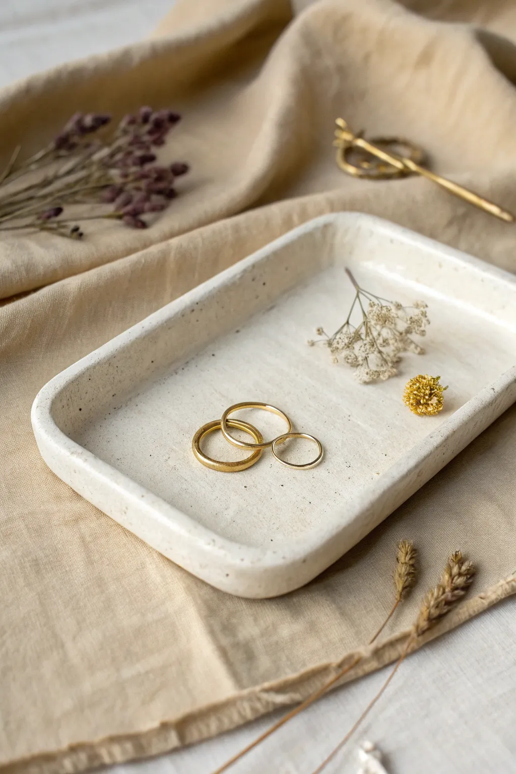 Handmade slab tray with stamped texture, styled for rings, a key, and a tiny dried bloom.