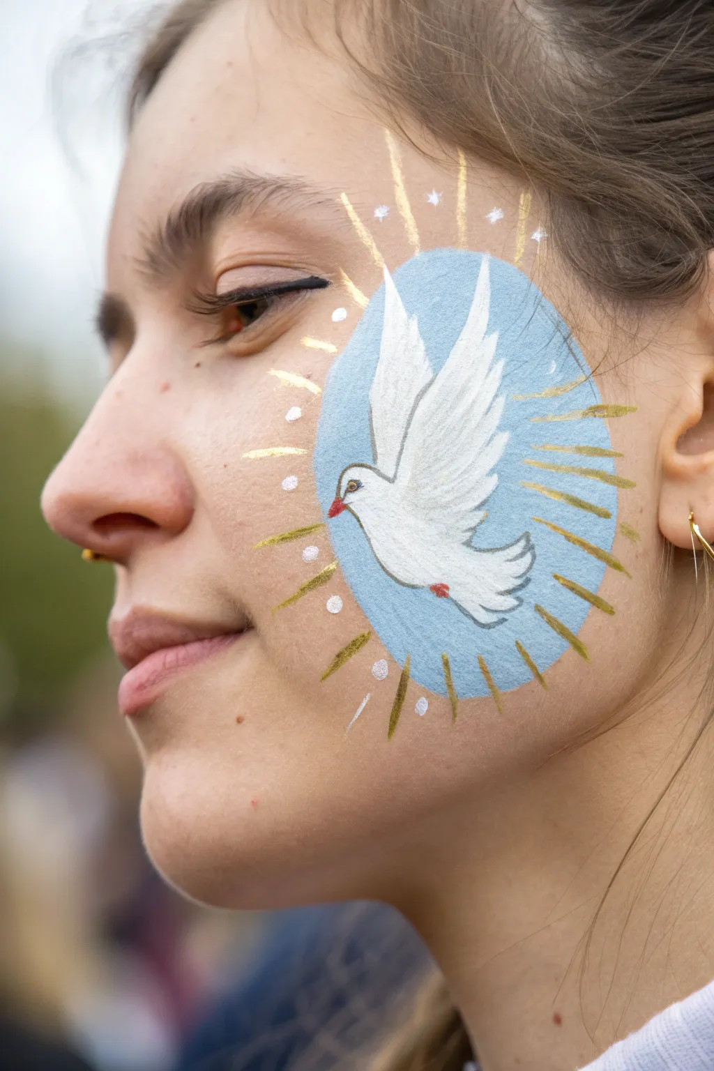 Dove of Peace face paint: crisp white silhouette with golden rays on a soft sky-blue wash