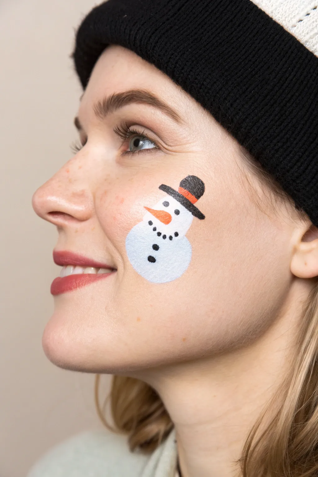 Minimal snowman cheek art with cozy scarf and icy blue shadow, perfect for chic holiday face paint